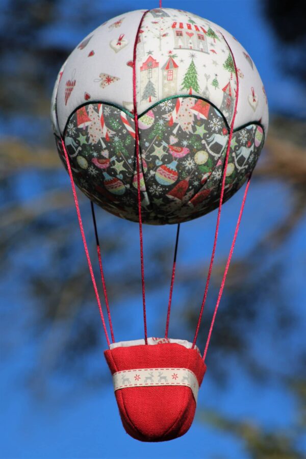 Montgolfière de décoration Maisons et petits cœurs, sur le thème de Noël. Travail d'incrustation de tissu sur une boule de polystyrène. Atelier à Villefranque (64)