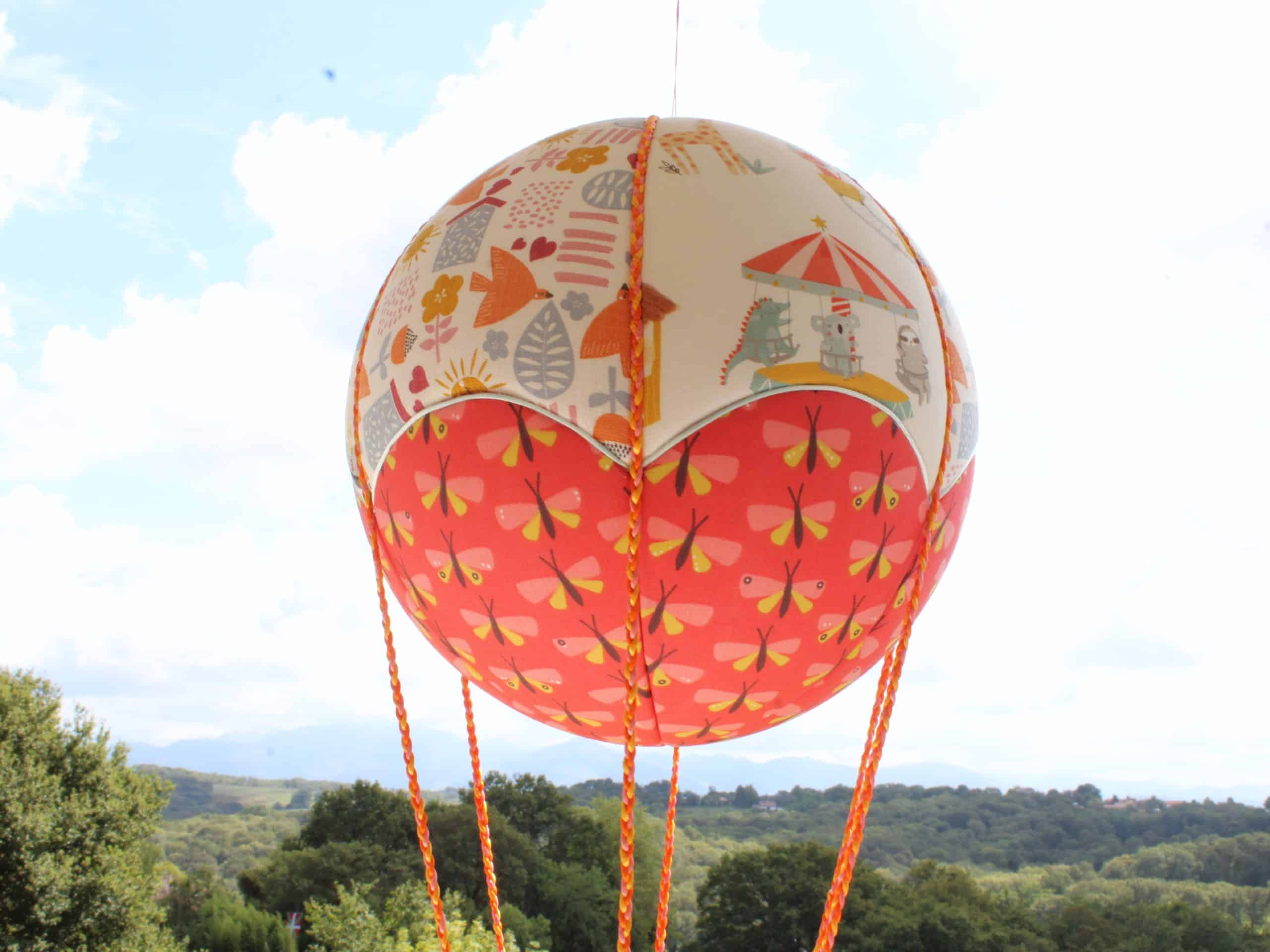 Tissus imprimés manèges et papillons dans les tons d'orange, pour une jolie montgolfière de décoration. Cadeau de naissance original. Atelier à Villefranque (64)