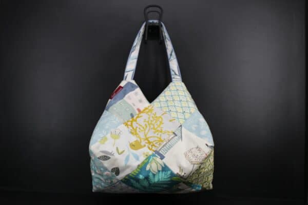 Sac en tissu Patchwork, doublé et ouatiné. Poches intérieures zippées et doublées. Un mousqueton permet d'accrocher les clefs. Atelier à Villefranque (64)